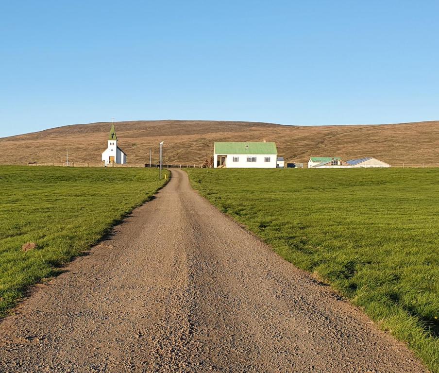 una strada sterrata in un campo con una chiesa di Tjörn 1 a Hvammstangi