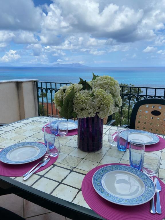 un tavolo con piatti e bicchieri e un vaso di fiori di voglia di vacanze a Gioiosa Marea