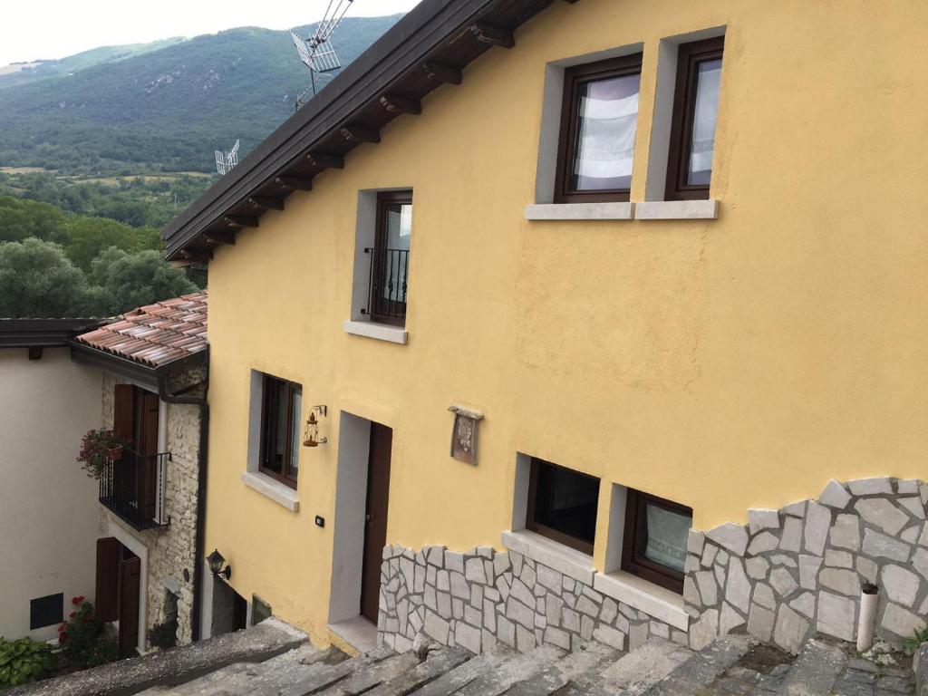 a yellow house with windows and a stone wall at ANTICA NEVIERA HOUSE in Castel di Sangro