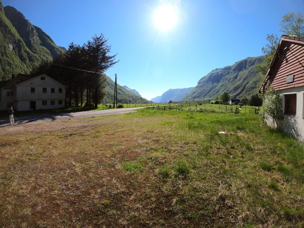 un campo con una casa y montañas en el fondo en Ørsdalen Turistsenter en Vikeså