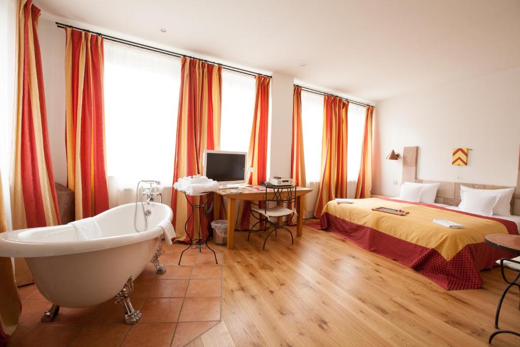 a bathroom with a tub and a bedroom with a bed at Hotel Drei Raben in Nürnberg