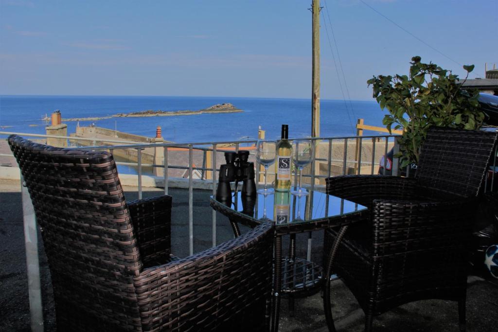 a table with two chairs and a bottle of wine at Bellevue Holiday Cottage in Gardenstown