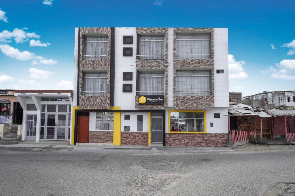 a tall white building with yellow doors on a street at Maximus Inn in Sechura