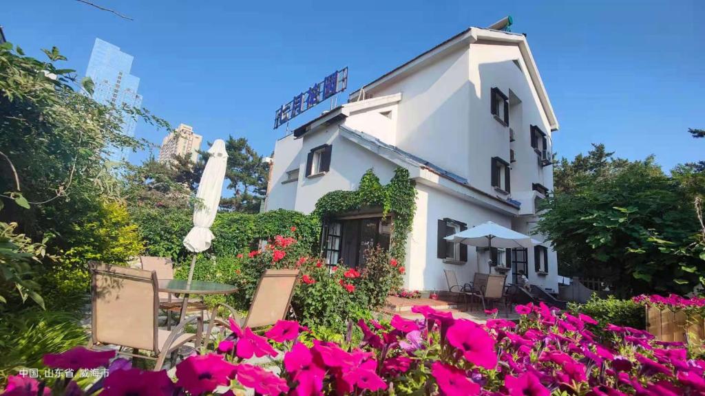 ein Gebäude mit rosa Blumen davor in der Unterkunft July Inn Weihai in Weihai