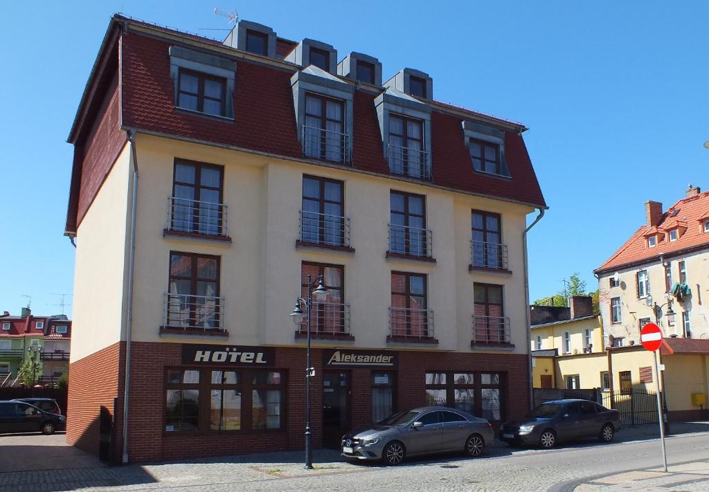 a building on a street with cars parked in front of it at Hotel Aleksander in Ustka