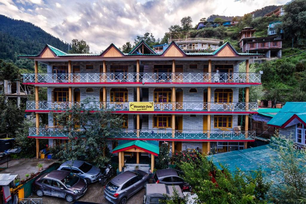 a large building with cars parked in front of it at Mountain Dew Guest House in Manāli