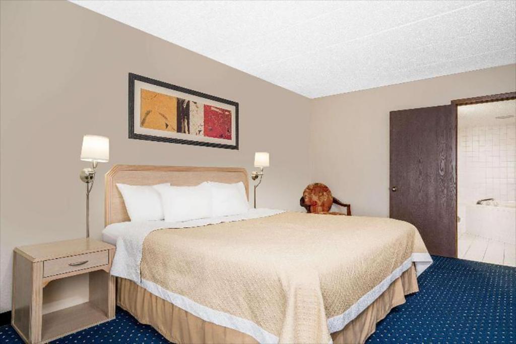 um quarto de hotel com uma cama e um cão sentado nela em Norwood Inn & Suites La Crosse em La Crosse