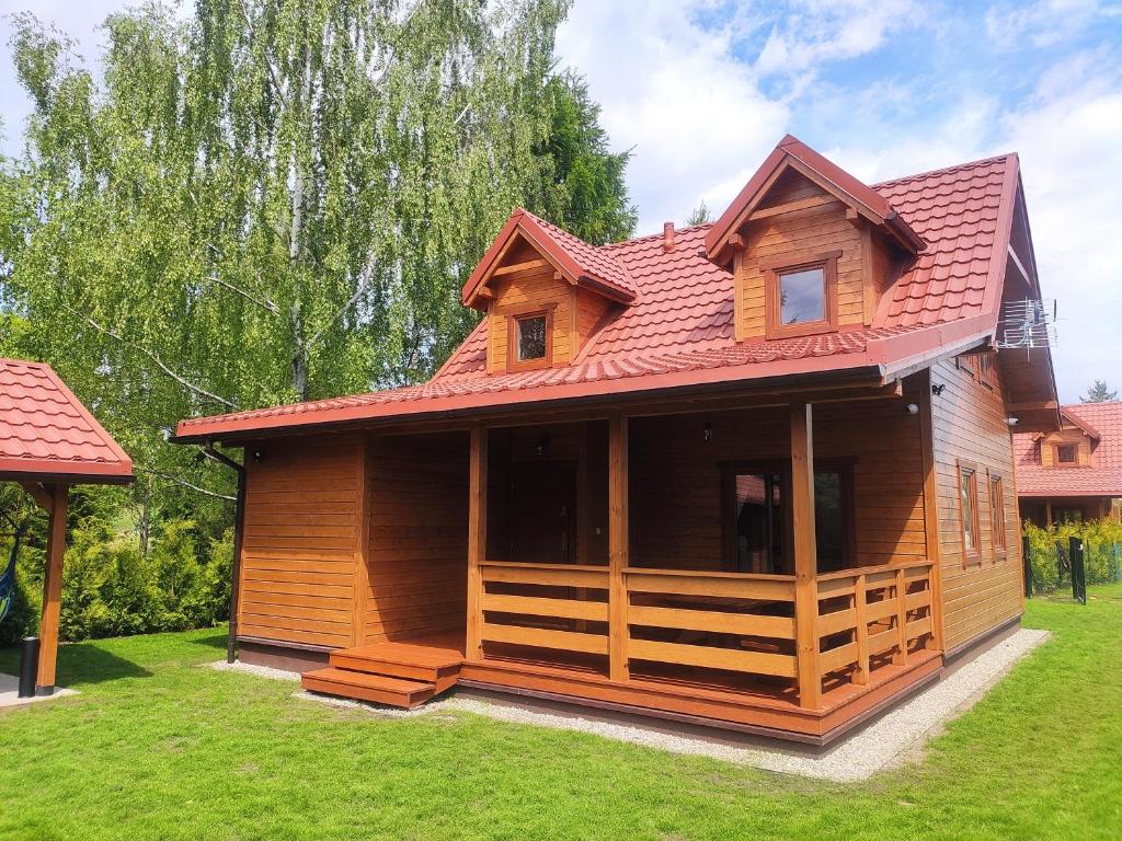 a wooden house with a red roof on a yard at Zielona Martanka in Pasym