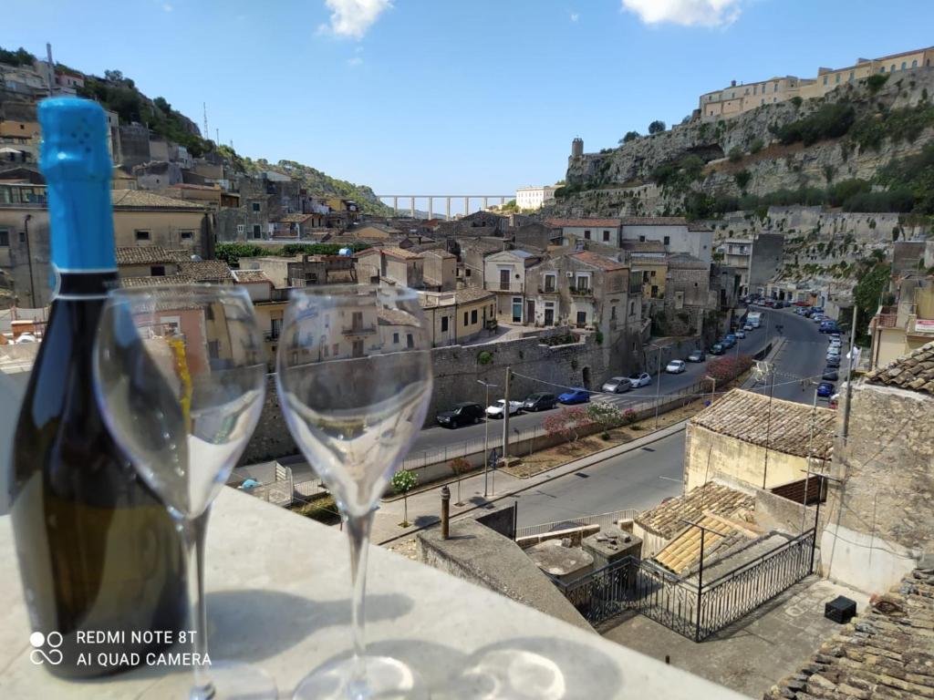 a wine glass sitting on a ledge with a view of a city at TERRA SICULA - vacanze modicane in Modica