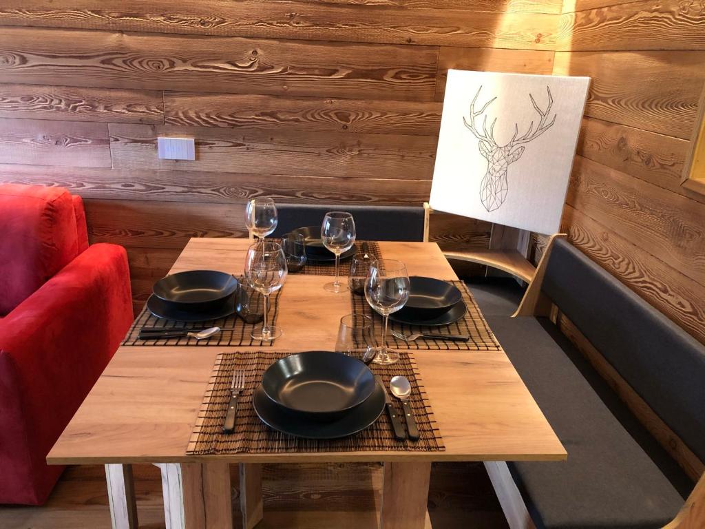 Una mesa de madera con platos y copas de vino encima. en Les Marmottes, en Breuil-Cervinia