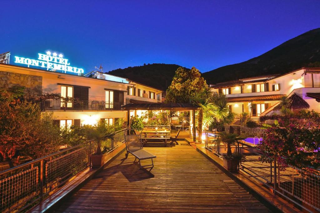 a wooden walkway leading to a hotel at night at Eco Hotel Montemerlo in Fetovaia