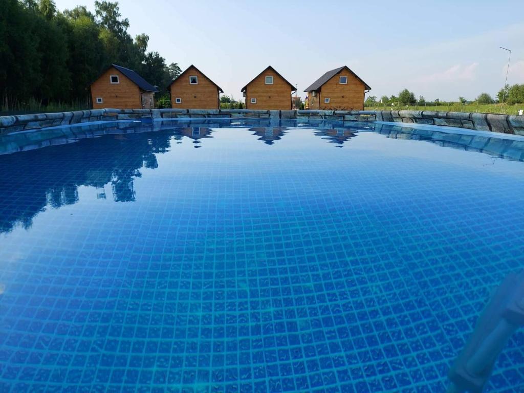 duży basen z domami w tle w obiekcie GRABSKA OSADA APARTAMENTY - 100m od Suntago Park-domki ogrzewane całoroczne w Mszczonowie