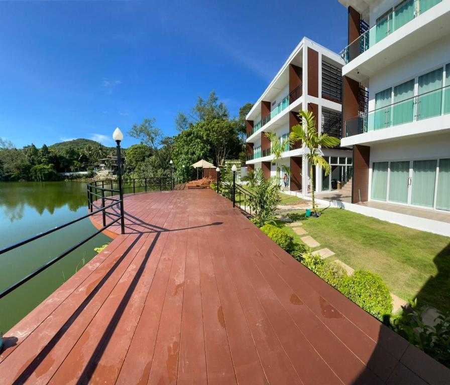 una pasarela de madera junto a un edificio junto a un cuerpo de agua en Pure Laguna Residence by Nice Sea Resort en Srithanu