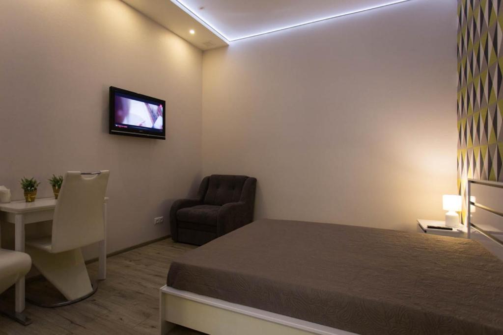 a bedroom with a bed and a chair and a television at New apartments in the city center - Kuznechna str. 26/1 in Kharkiv