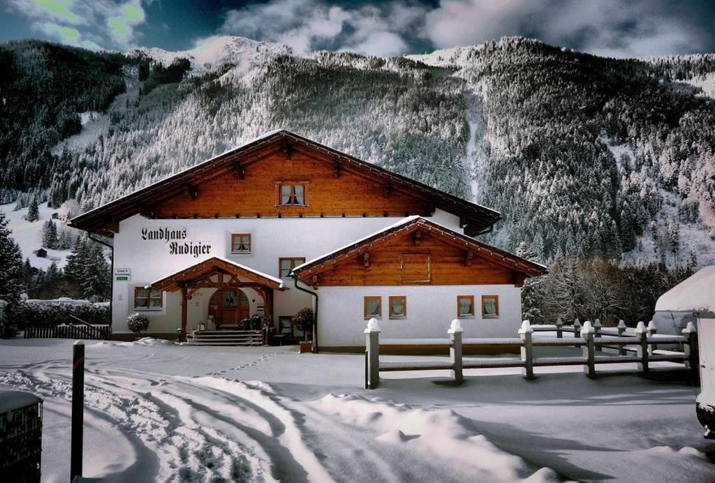 a building with a fence in front of a mountain at Landhaus Rudigier in Sankt Gallenkirch