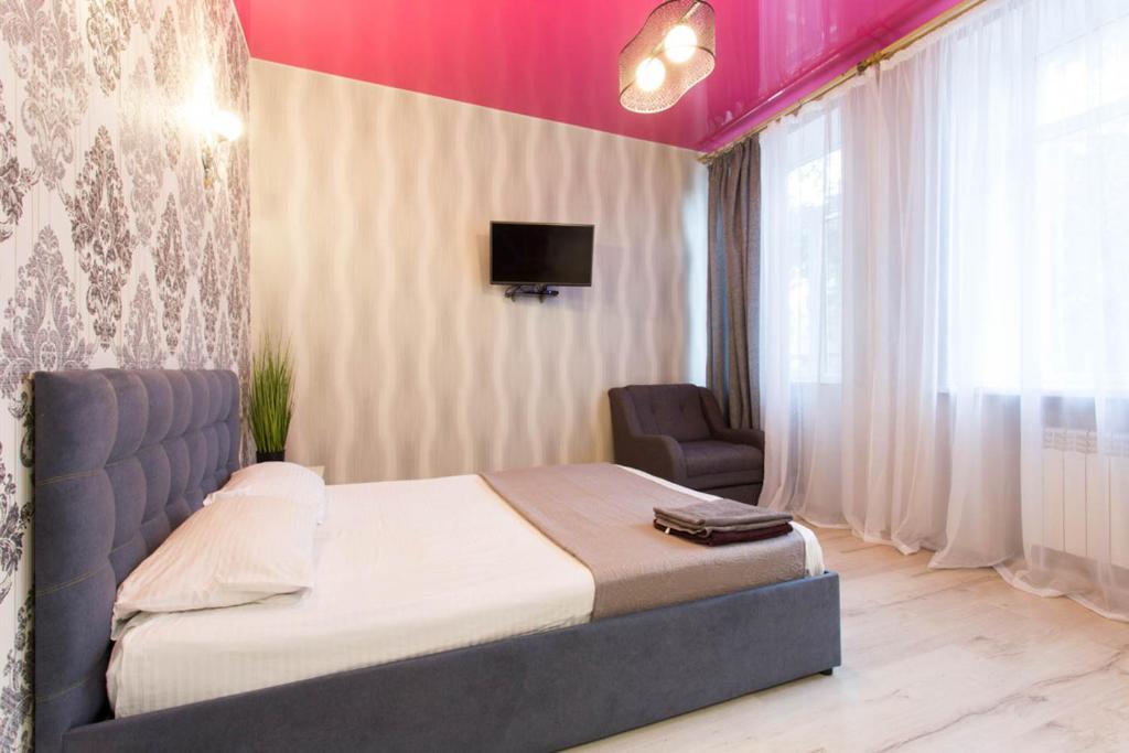 - une chambre avec un lit, une télévision et une chaise dans l'établissement Studio apartment in the Center - Heroiv Nebesnoi Sotni sq. 21/7, à Kharkov