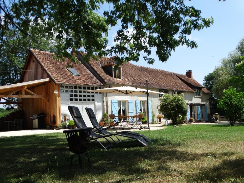 a house with a group of chairs in the yard at B&B Le Corbier in Herry