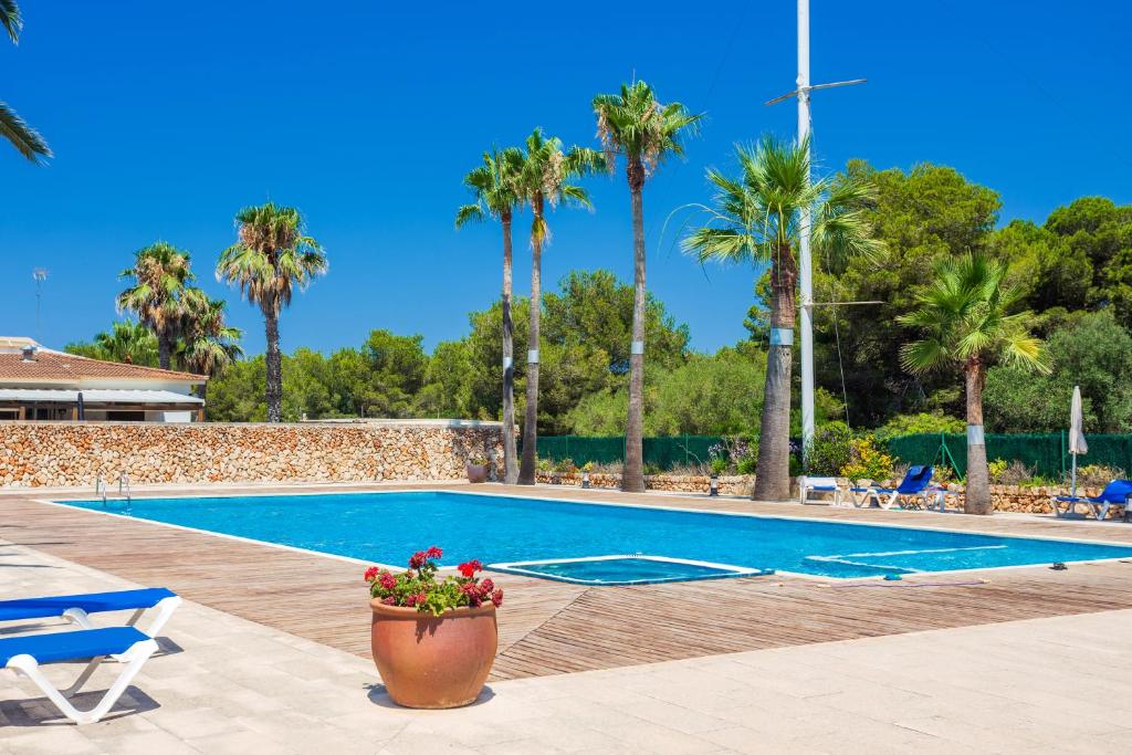 a swimming pool with palm trees in the background at Sa Perdiu 30 in Cala Santandria