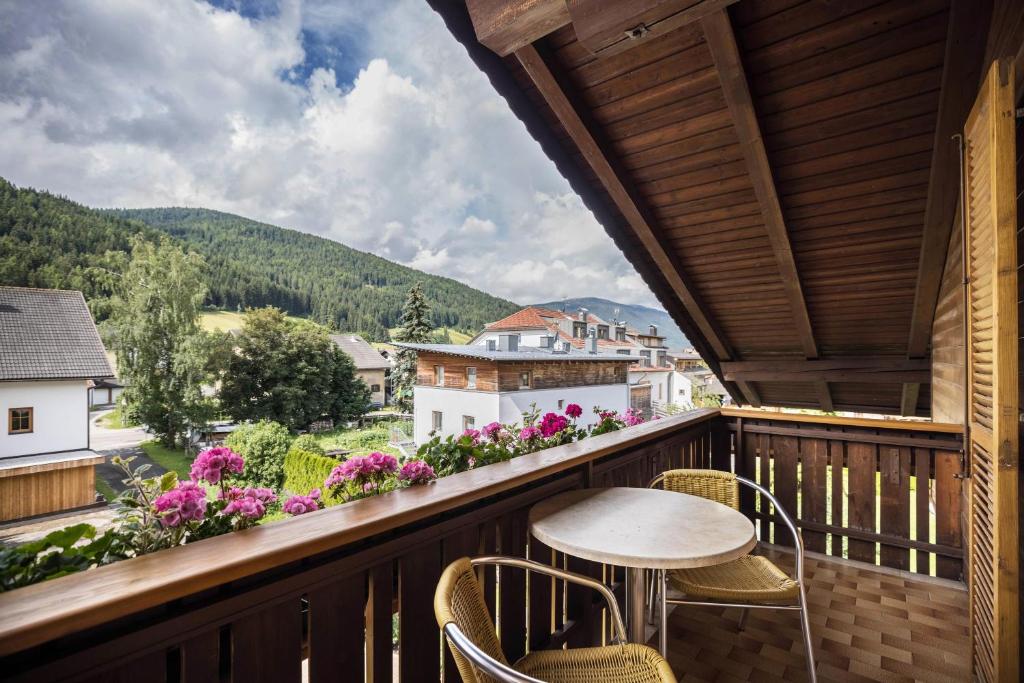 - un balcon avec une table, des chaises et des fleurs dans l'établissement Apt Hofer Marianna, à Villabassa
