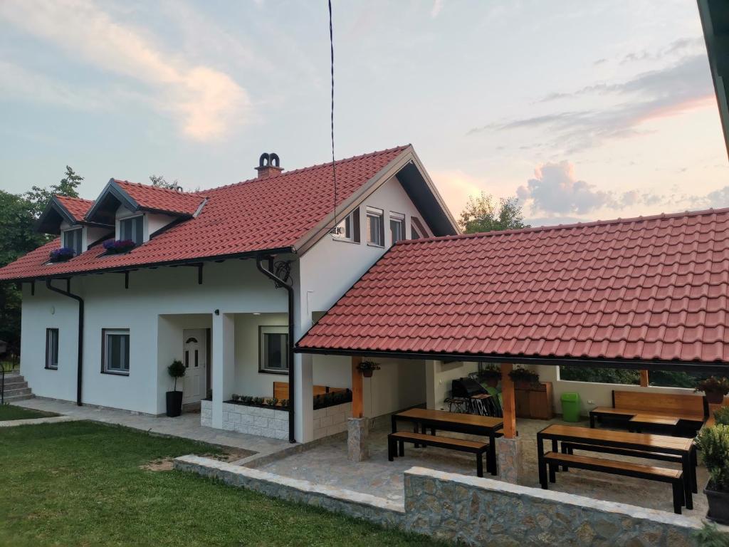 una casa con techo rojo y dos bancos en Stari Tršić, en TrÅ¡iÄ‡