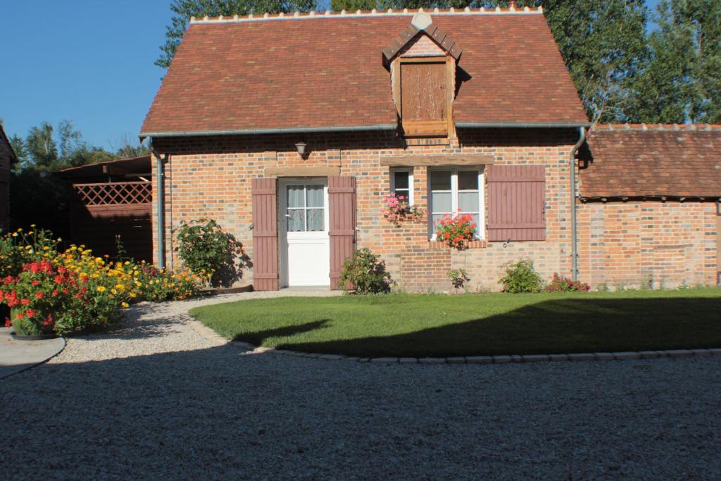 ein Backsteinhaus mit einer weißen Tür und einer Auffahrt in der Unterkunft Gîte des Belles Fontaines in Neung-sur-Beuvron