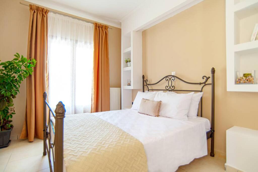 a bedroom with a bed with white sheets and a window at La MAISON di Angelo STUDIO in Ayios Kirikos