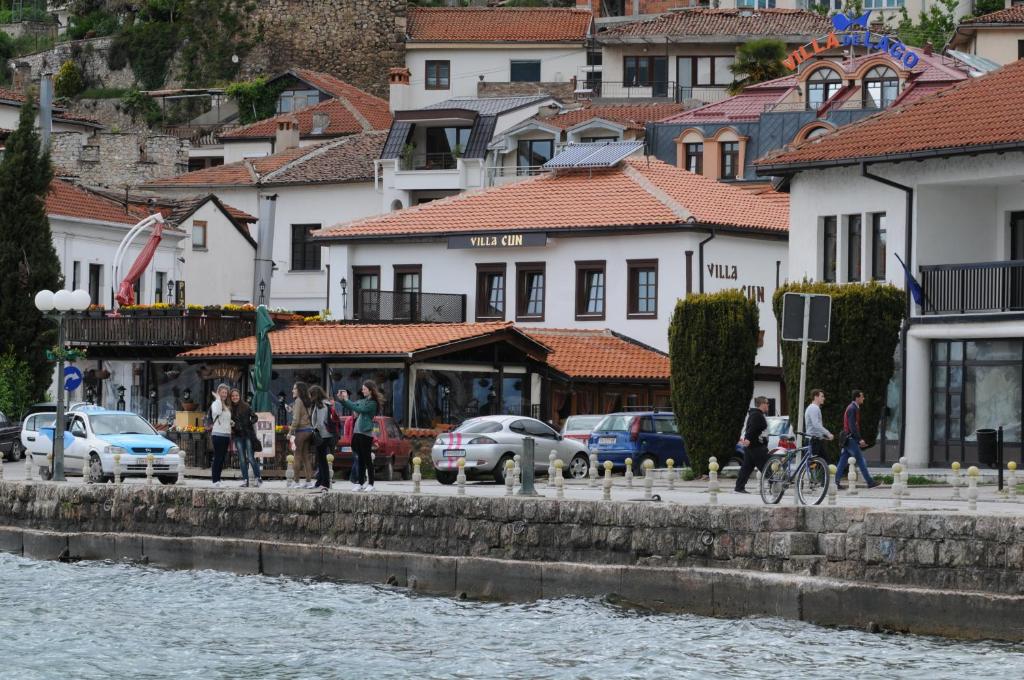 a group of people walking on a sidewalk next to a river at House Cun in Ohrid