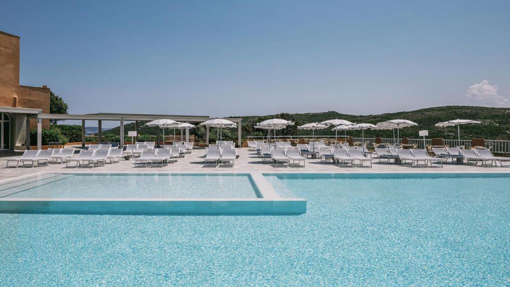 - une piscine avec des chaises longues et des parasols dans l'établissement MClub Marmorata, à Santa Teresa Gallura