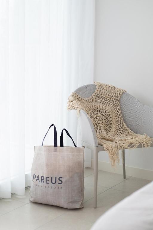 a tote bag next to a chair with a dress at Pareus Beach Resort in Caorle