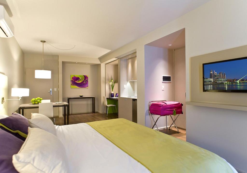 1 dormitorio con 1 cama grande y 1 maleta rosa en Bulnes Eco Suites en Buenos Aires