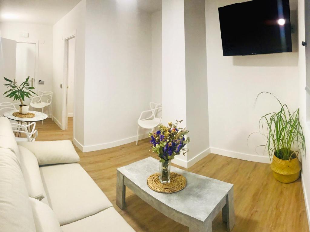 a living room with a couch and a table with flowers at Apartamentos Santander Maliaño Suites 3000 in Maliaño