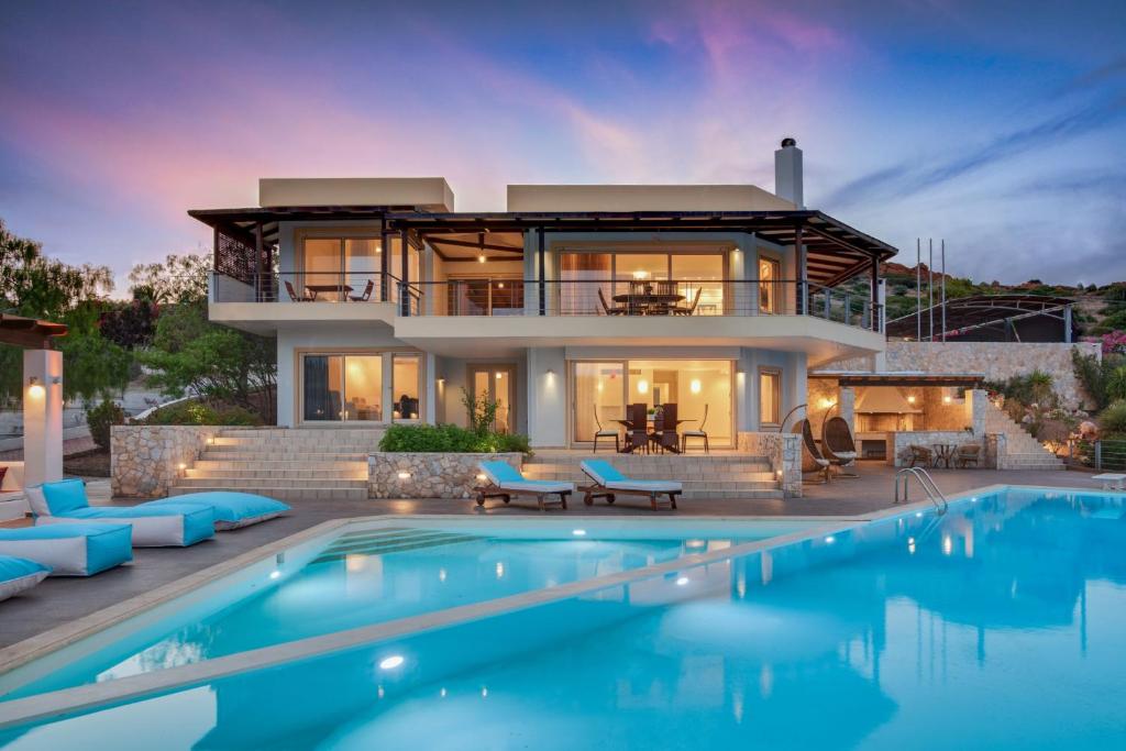 a house with a swimming pool in front of a house at Cape Sounio Villa in Sounio