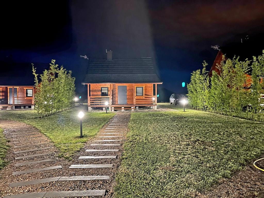 una cabaña de madera por la noche con luces en el patio en Domki Mazurskie Zacisze Jeziora Sunowo, en Ełk