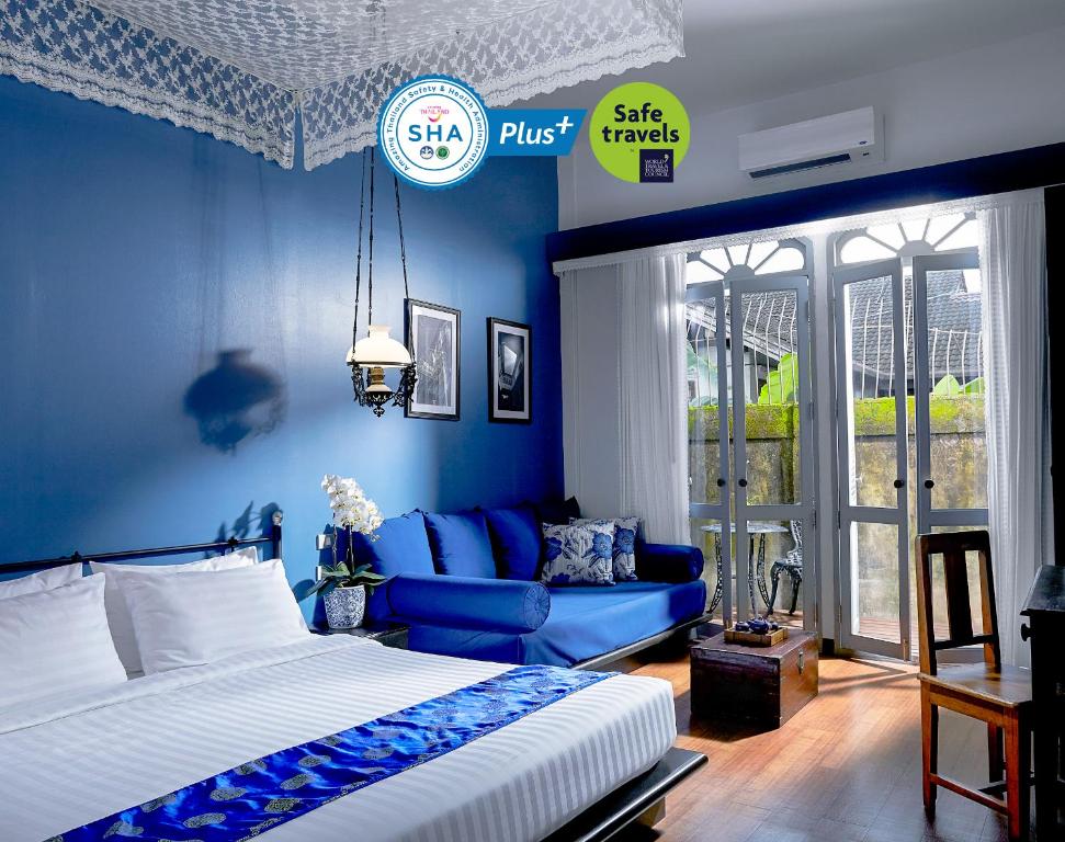 Dormitorio azul con cama y sofá en The Memory at On On Hotel en Phuket