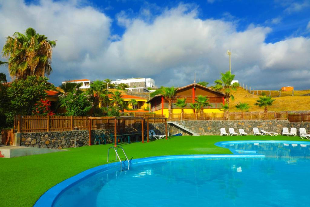 a resort with a large swimming pool and green grass at Hotel Casas do Sol in São Filipe