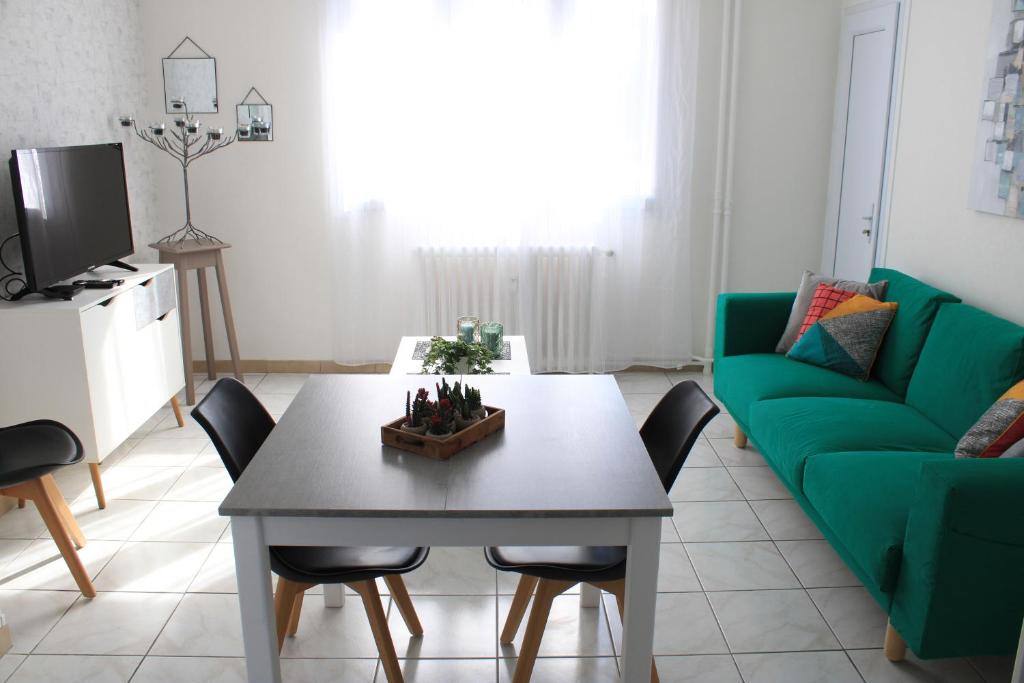 salon ze stołem i zieloną kanapą w obiekcie L'appartement d'Alexander w Troyes