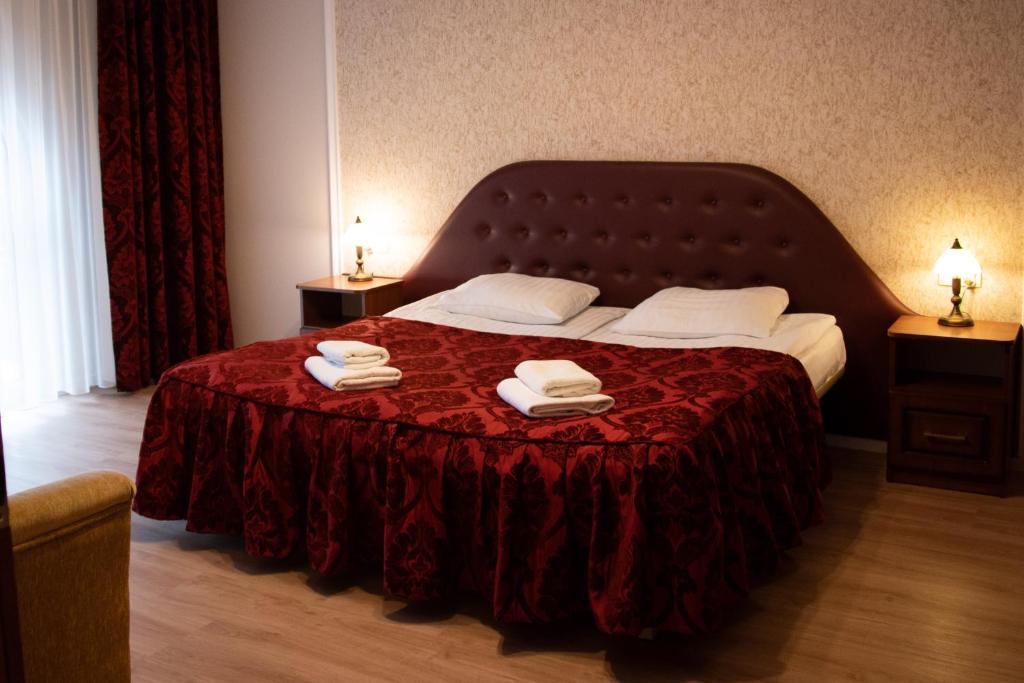 a bedroom with a bed with a red blanket and two towels at Gościniec Kaszubski in Kartuzy