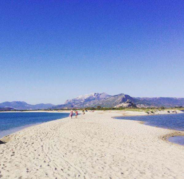 pessoas caminhando em uma praia com montanhas ao fundo em holiday home em Posada