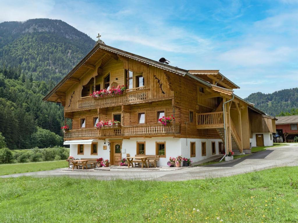 ein großes Holzgebäude mit Tischen davor in der Unterkunft Bauernhof Unterstegen in Söll