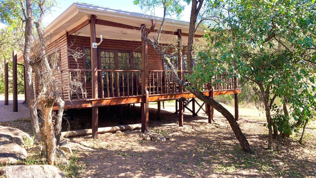 a wooden house with a deck in the woods at Hope Haven Cottage in Nelspruit