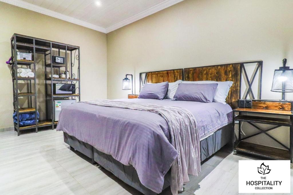 a bedroom with a large bed with a purple blanket at 42 Upon Williams Guesthouse in Klerksdorp