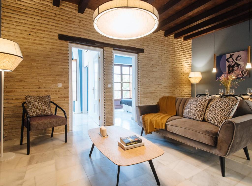ein Wohnzimmer mit einem Sofa und einem Tisch in der Unterkunft Suites Triana Sevilla Apartments in Sevilla