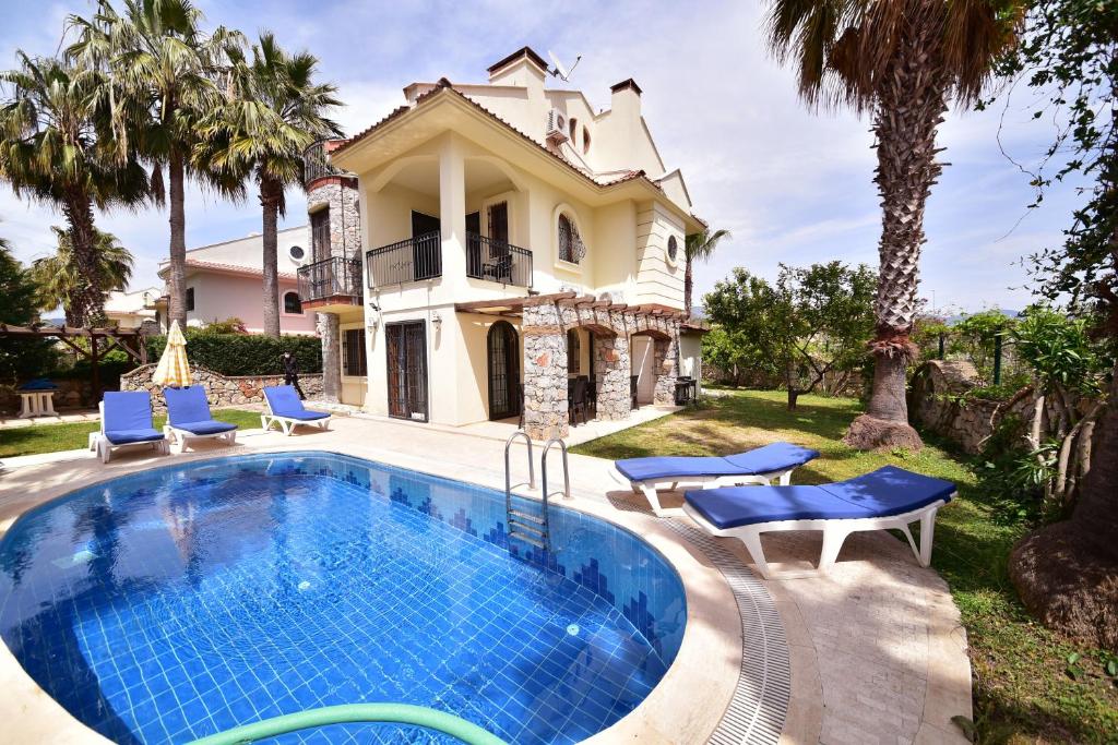 una piscina frente a una casa con palmeras en Villa Phoenix en Fethiye