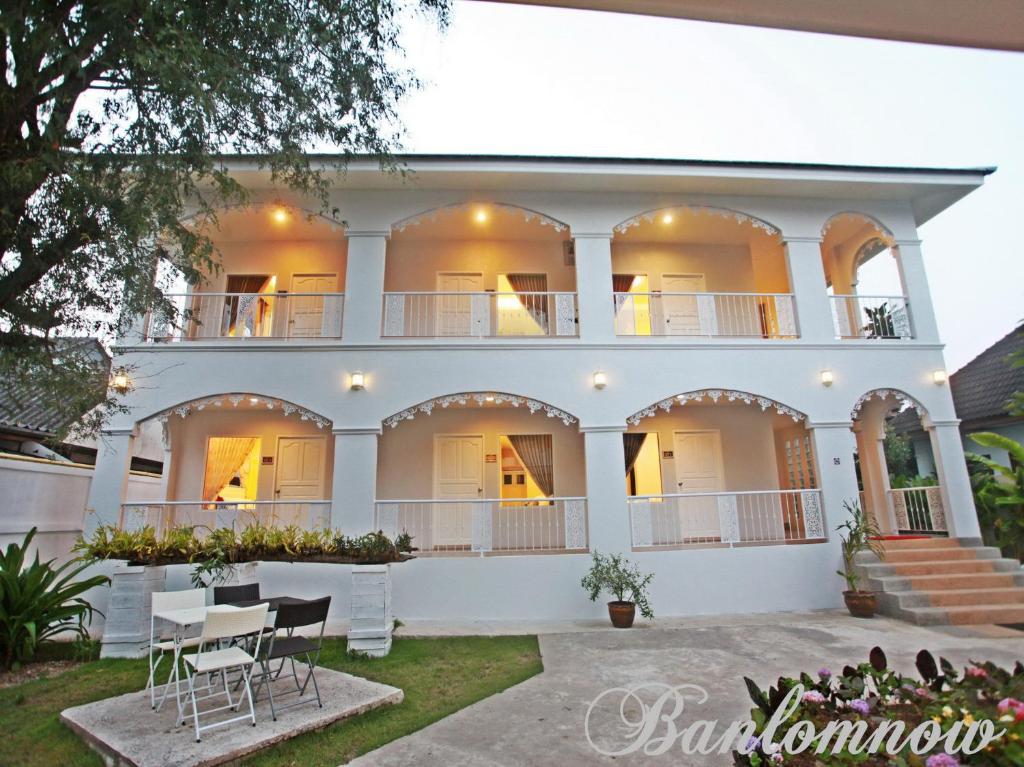 Casa blanca grande con mesa y sillas en Banlomnow, en Chiang Rai