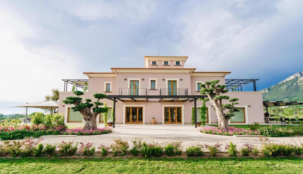 uma grande casa branca com árvores e flores em Villa Eleonora Paestum em Paestum