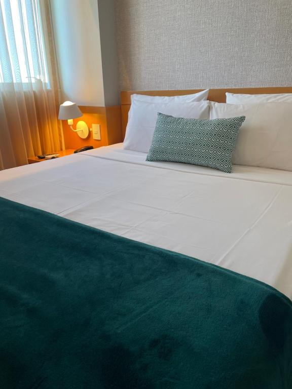 a large white bed with two pillows on it at Flat IATE CLUBE Home Experience Praia do Canto in Vitória