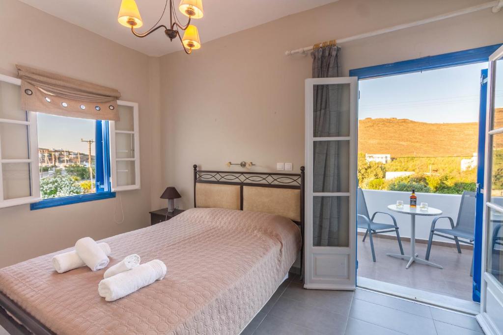 a bedroom with a bed and a balcony with a table at Meltemi Hotel Kythnos in Loutra