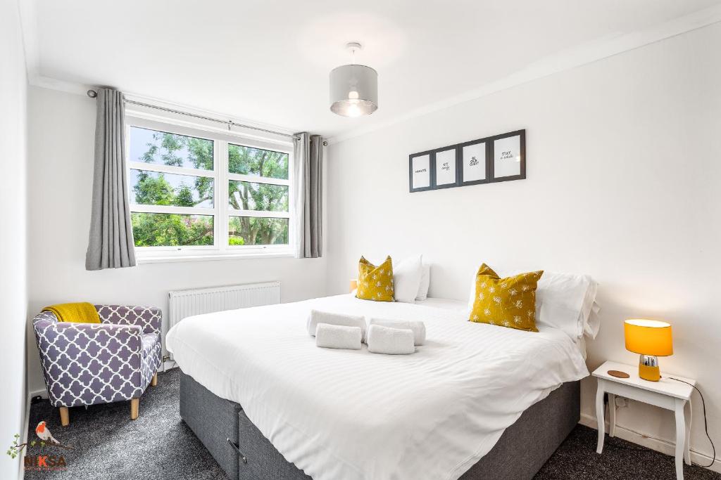 um quarto com uma grande cama branca com almofadas amarelas em NIKSA Serviced Accommodation - 3 bedroom house em Welwyn Garden City