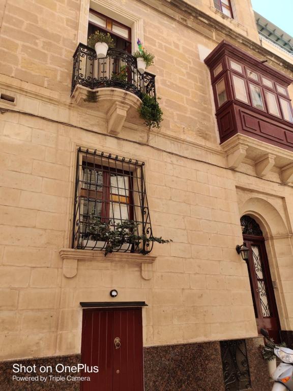 a building with two windows and a balcony at Semi-basement, cosy apartment interconnected to our residence a traditional Maltese townhouse in Senglea