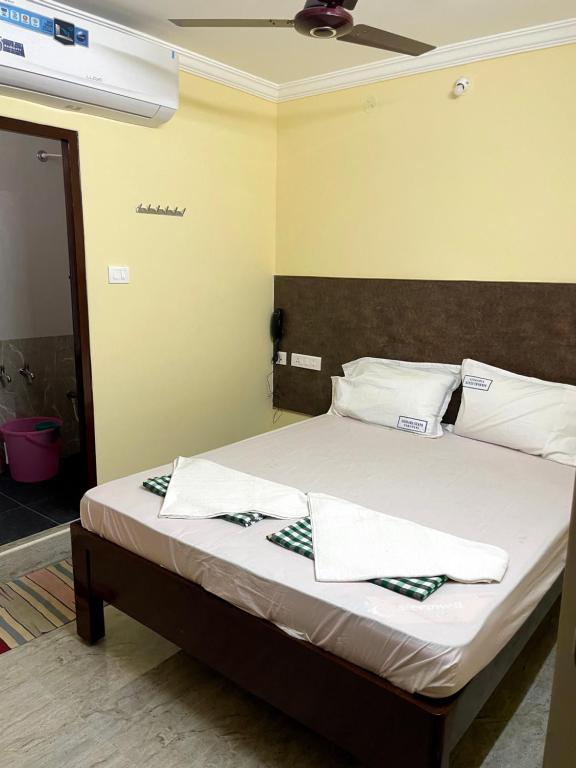 a bedroom with a bed with white sheets and pillows at Newly opened - Sikhara Stays in Tirupati